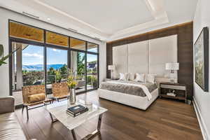 Bedroom featuring dark hardwood / wood-style flooring, a mountain view, a tray ceiling, and access to outside