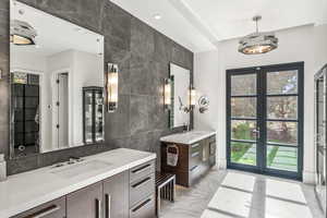 Bathroom with tile walls, vanity, plenty of natural light, and french doors