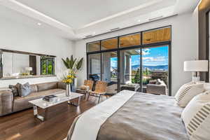 Bedroom featuring dark hardwood / wood-style floors, a raised ceiling, and access to outside