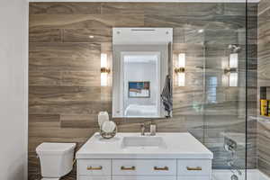 Full bathroom with shower / bath combination, vanity, tile walls, and toilet