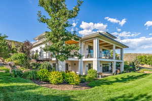 Rear view of property featuring a balcony and a lawn