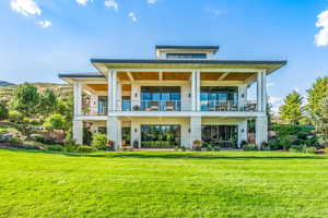 Back of property with a lawn, a balcony, and a patio area