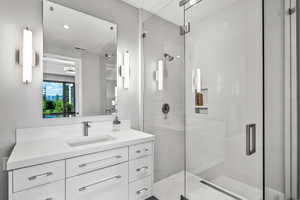 Bathroom featuring a shower with door and vanity