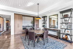 Dining space with sink, concrete floors, a raised ceiling, a barn door, and wooden ceiling