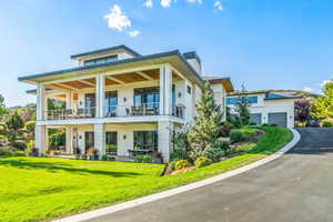 View of front of property featuring a garage, a front yard, and a balcony