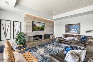 Living room featuring a raised ceiling, wooden ceiling, and a high end fireplace