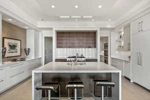 Kitchen featuring white cabinetry, sink, a breakfast bar, and an island with sink