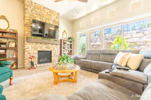 Living room featuring ceiling fan, a stone fireplace, and hardwood / wood-style floors