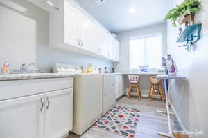 Washroom featuring cabinets, sink, independent washer and dryer, and light hardwood / wood-style floors