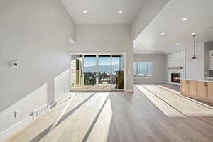 Unfurnished living room with a mountain view, a towering ceiling, a fireplace, and light hardwood / wood-style floors