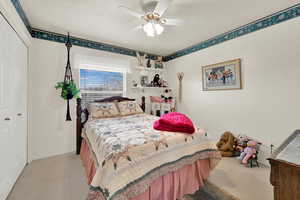 Bedroom featuring ceiling fan, light carpet, and a textured ceiling