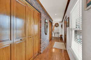 Hallway featuring ornamental molding, brick wall, and a healthy amount of sunlight