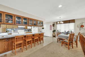 Carpeted dining space with an inviting chandelier and a textured ceiling