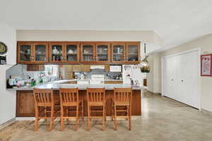 Kitchen featuring white appliances, a kitchen breakfast bar, kitchen peninsula, and decorative backsplash