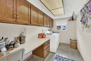 Clothes washing area with cabinets, independent washer and dryer, and light wood-type flooring