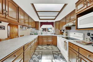 Kitchen with sink, white appliances, decorative backsplash, and light wood-type flooring