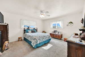 Carpeted bedroom with ceiling fan and a textured ceiling