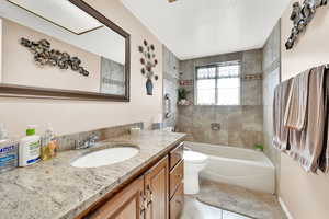 Full bathroom with toilet, tiled shower / bath, a textured ceiling, vanity, and tile patterned flooring