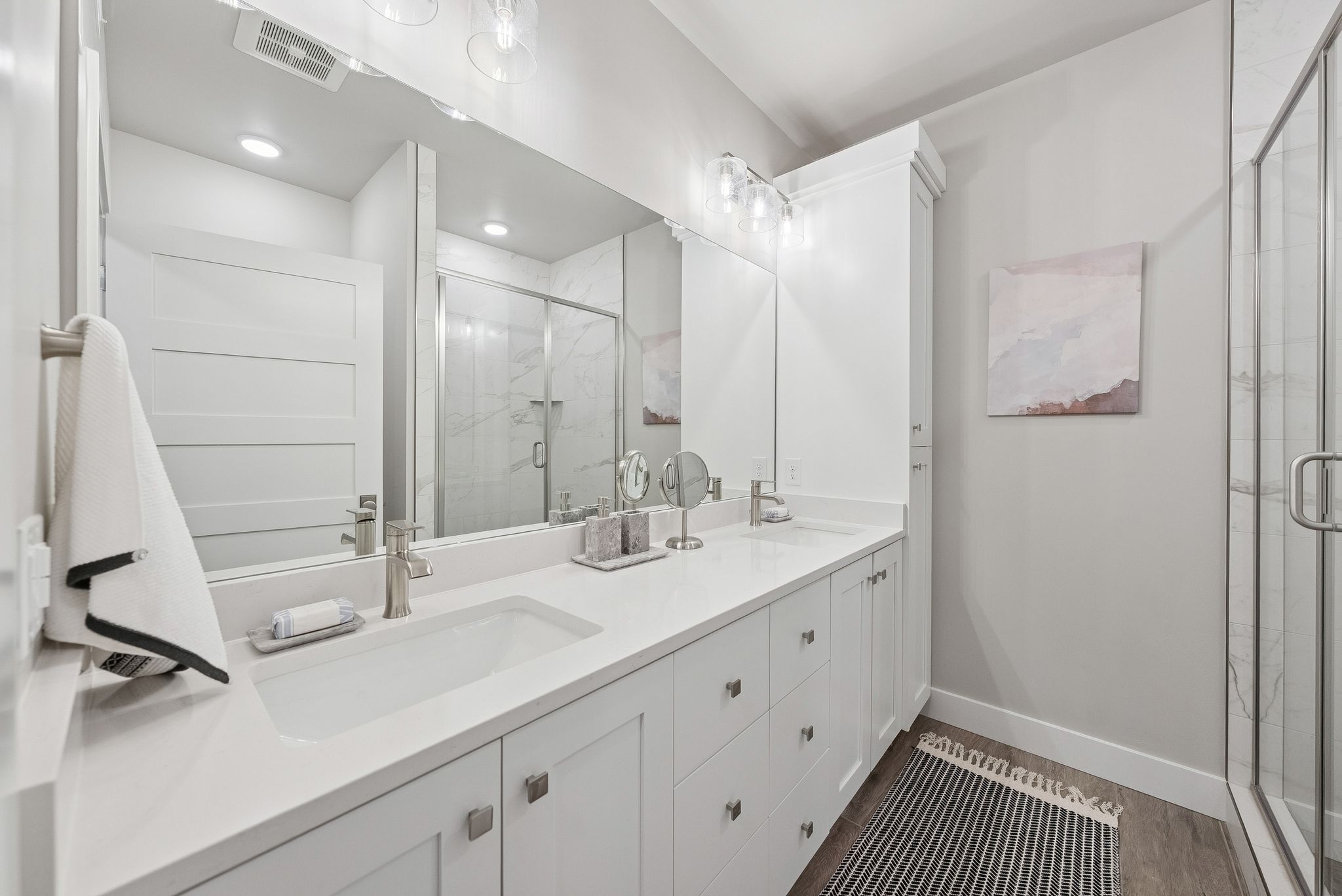 Full bathroom with double vanity, a shower stall, and wood finished floors