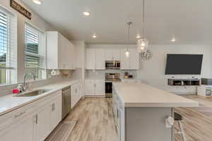 Kitchen with pendant lighting, white cabinetry, sink, a center island, and stainless steel appliances