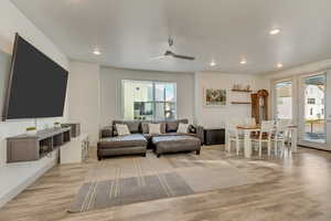 Living room featuring a wealth of natural light, light hardwood / wood-style floors, and ceiling fan