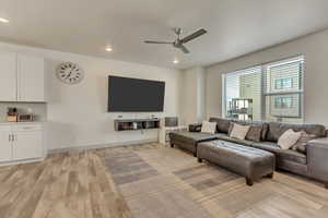 Living room with ceiling fan and light hardwood / wood-style flooring