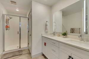 Bathroom with vanity, a shower with shower door, and hardwood / wood-style floors