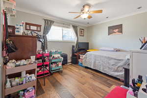 Bedroom featuring ceiling fan, ornamental molding, and wood finished floors