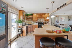 Kitchen featuring open shelves, a sink, light countertops, brown cabinets, and black appliances