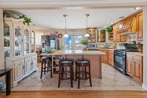 Kitchen with a center island, stainless steel appliances, tasteful backsplash, light countertops, and a kitchen bar