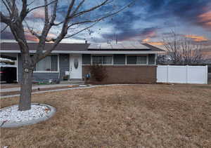 Single story home with a lawn and solar panels