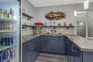 Wet bar/Kitchen equipped with a sink, beverage fridge, custom cabinetry, and stylish pendant lighting.