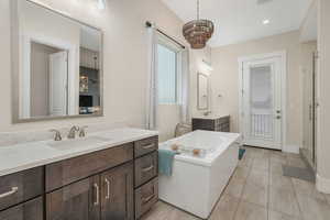 Primary en suite bathroom with dual vanities, tile flooring, shower with stand-alone bathtub, and private deck entrance