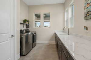 Enormous laundry room featuring custom cabinets, independent washer and dryer, sink, and tons of counter space to do all of your folding.