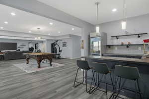 Wet bar/Kitchen equipped with a sink, beverage fridge, custom cabinetry, and stylish pendant lighting.