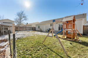 Back of house with a playground and a lawn