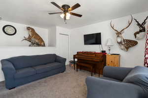 Carpeted living room featuring ceiling fan