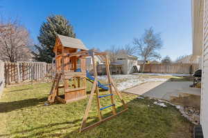 View of jungle gym featuring a patio, a yard, and a storage unit