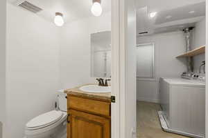 Bathroom with vanity, washing machine and clothes dryer, and toilet