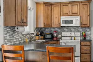 Kitchen featuring white appliances, sink, and backsplash