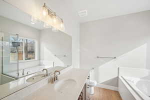 Bathroom with vanity, toilet, hardwood / wood-style floors, and a tub