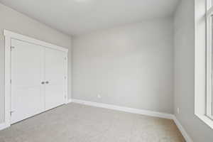 Unfurnished bedroom featuring light carpet and a closet