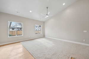 Empty room with lofted ceiling, ceiling fan, light hardwood / wood-style flooring, and a healthy amount of sunlight