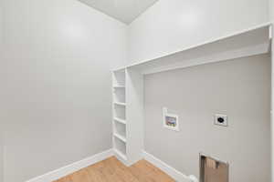 Clothes washing area featuring hookup for an electric dryer, hookup for a washing machine, and hardwood / wood-style floors