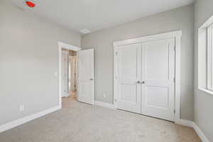 Unfurnished bedroom featuring light carpet and a closet