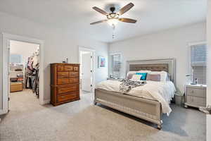 Bedroom featuring a spacious closet, light carpet, ceiling fan, and a closet