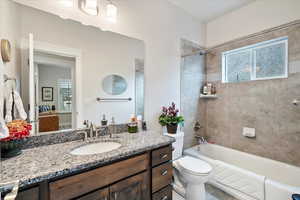 Full bathroom with tiled shower / bath combo, vanity, a wealth of natural light, and toilet