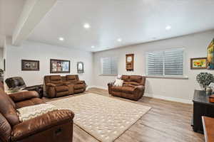 Living room with beam ceiling and light wood-type flooring