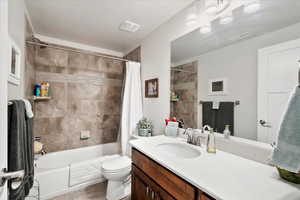 Full bathroom with vanity, shower / bath combination with curtain, a textured ceiling, and toilet