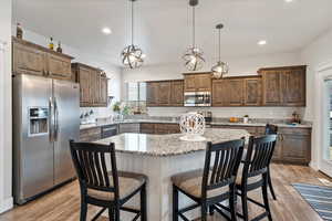 Kitchen featuring light hardwood / wood-style floors, decorative light fixtures, stainless steel appliances, and a center island